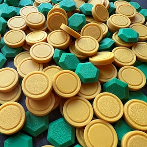 May include: A collection of yellow and green game pieces. The yellow pieces are round with a raised edge, while the green pieces are hexagonal. The pieces are scattered across a dark surface, suggesting a board game or craft project.