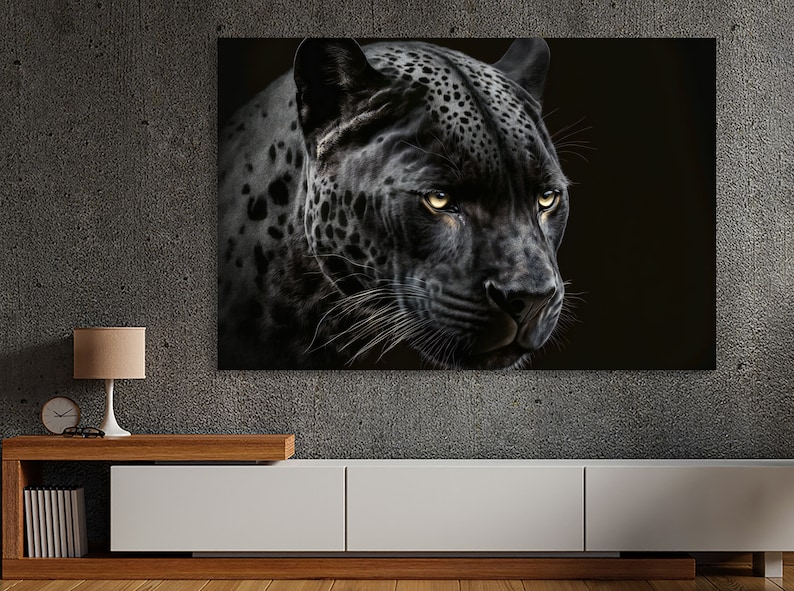 May include: A canvas print featuring a close-up of a black jaguar's face. The jaguar has yellow eyes and a black coat with dark spots. The background is black, emphasizing the animal's features. The artwork is displayed on a wall above a white cabinet.