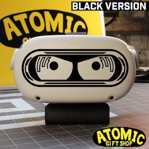 May include: Black and white robot eye design decal for an Oculus Quest 2 virtual reality headset. The decal is applied to the front of the headset and features a pair of robot eyes with a black background.