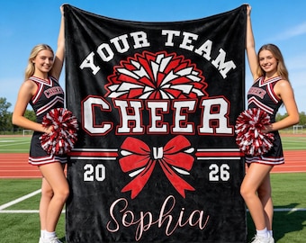 Puede incluir: Una manta de forro polar negra con el texto blanco YOUR TEAM CHEER, un gráfico de pompón rojo y blanco, un lazo rojo grande, los números 20 y 26, y el nombre Sophia en letra cursiva. El diseño utiliza colores negro, rojo y blanco.