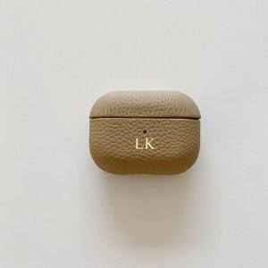 May include: A tan leather Airpods case with the initials "LK" embossed on the front.