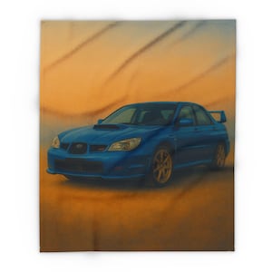 Op de afbeelding: Een blauwe auto met gouden velgen staat op een deken. De auto, een sedan met een achterspoiler, staat tegen een oranje en bruine achtergrond. De deken is een zacht, comfortabel item.