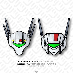 May include: Two glossy stickers featuring stylized robot head designs. One is white with a green mouth, red dot, and yellow accents. The other is white with a red stripe and green accents. Both have gray antenna-like structures.