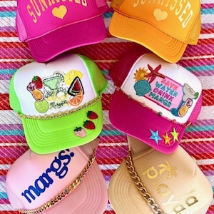 May include: Six colorful trucker hats with various designs and embellishments. The hats feature a variety of themes, including summer, beach, and cocktails. The hats are all made of a mesh material and have a curved brim.