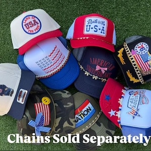 May include: A selection of red, white, and blue trucker hats with patriotic themes. Designs include the American flag and the text "Made in the U.S.A.". The image also displays the text "Chains Sold Separately".
