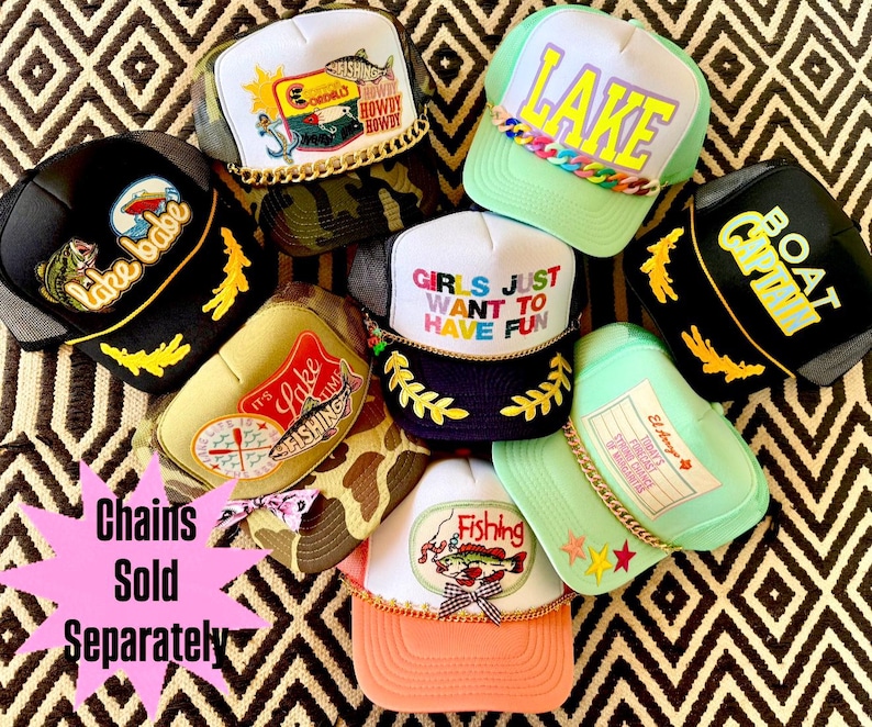 May include: A collection of trucker hats with various designs and text, including "Lake Babe," "Lake," and "Girls Just Want to Have Fun." The hats feature mesh backs, embroidered patches, and decorative chains.