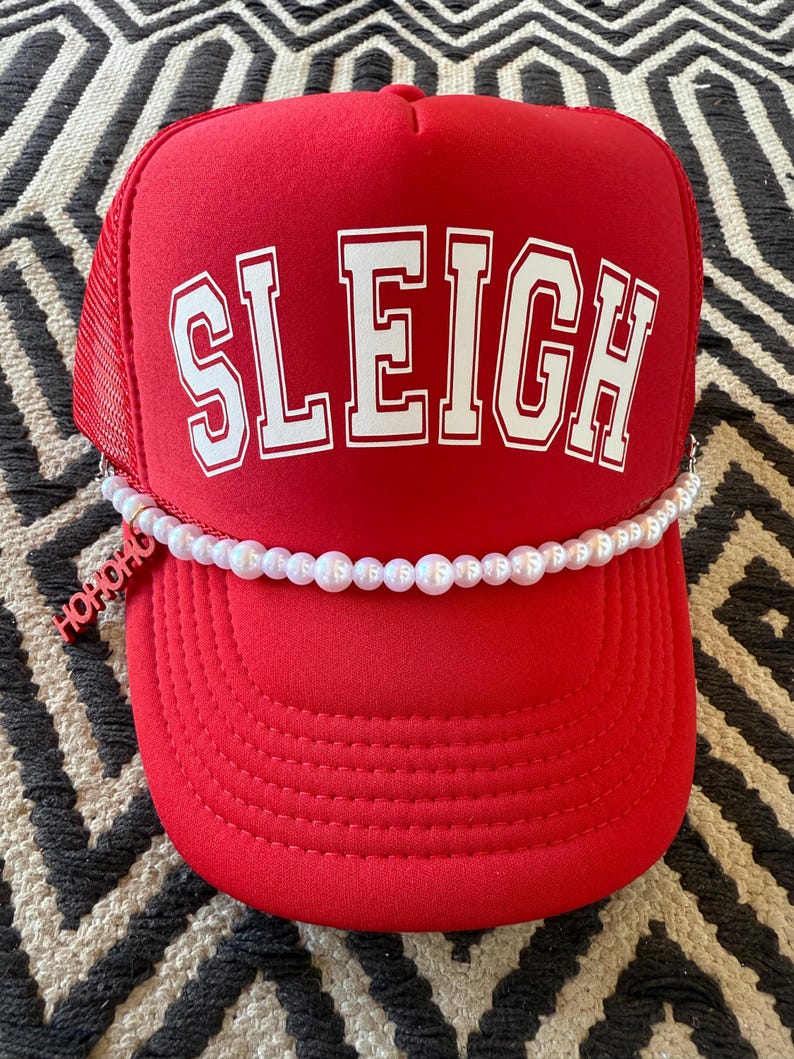 May include: Red trucker hat with a white "SLEIGH" logo and a pearl necklace trim. The hat has a black mesh back.