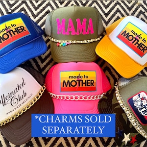 May include: Six different trucker hats with various designs and colors. The hats feature the text "made to mother", "mama", "caffeinated club", and "mama tried". The hats are decorated with gold chains and charms. *CHARMS SOLD SEPARATELY*.