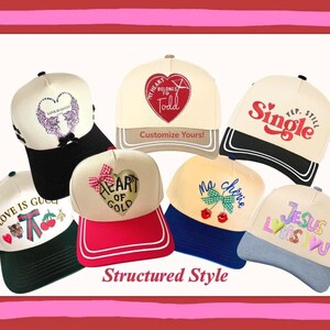 May include: Collection of baseball caps with various designs and text, including "LOVE IS GUCCI", "MY HEART BELONGS TO Todd", "Single", "HEART OF GOLD", "Ma chérie", and "JESUS LOVES YOU". The caps feature different color combinations and styles.