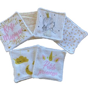 Puede incluir: Conjunto de seis almohadillas desmaquillantes de algod&oacute;n blanco con diferentes dise&ntilde;os en rosa y dorado. Los dise&ntilde;os incluyen un unicornio, una nube, una corona y las palabras "Rete Magique" y "Petite Princesse".