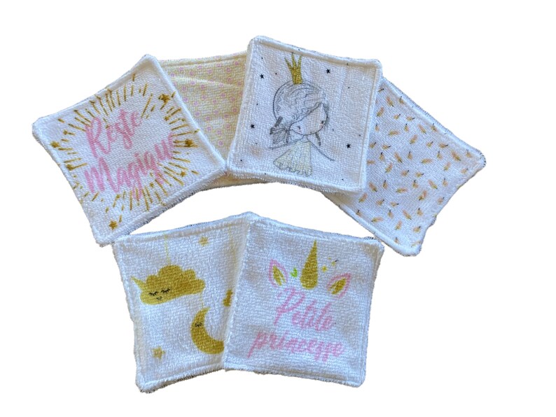 Puede incluir: Conjunto de seis almohadillas desmaquillantes de algod&oacute;n blanco con diferentes dise&ntilde;os en rosa y dorado. Los dise&ntilde;os incluyen un unicornio, una nube, una corona y las palabras "Rete Magique" y "Petite Princesse".