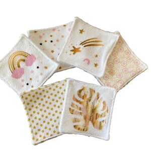 Puede incluir: Conjunto de seis almohadillas de algod&oacute;n blanco para desmaquillar con diferentes dise&ntilde;os dorados y rosados. Los dise&ntilde;os incluyen un arco&iacute;ris, estrellas, una estrella fugaz, una hoja y un patr&oacute;n geom&eacute;trico.