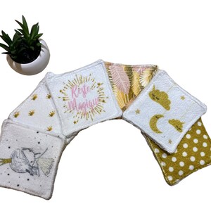 Puede incluir: Seis almohadillas de algod&oacute;n blanco para desmaquillar con diferentes dise&ntilde;os dorados y rosados. Los dise&ntilde;os incluyen una corona, estrellas, una nube, una luna creciente, una hoja de palma y el texto "Reste Magique".