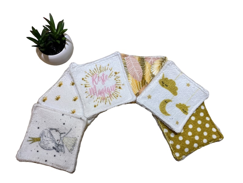 Puede incluir: Seis almohadillas de algod&oacute;n blanco para desmaquillar con diferentes dise&ntilde;os dorados y rosados. Los dise&ntilde;os incluyen una corona, estrellas, una nube, una luna creciente, una hoja de palma y el texto "Reste Magique".
