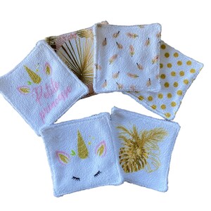 Puede incluir: Conjunto de seis almohadillas desmaquillantes de algod&oacute;n blanco con diferentes dise&ntilde;os. Los dise&ntilde;os incluyen un unicornio con el texto "Petite Princesse", una pi&ntilde;a y un patr&oacute;n de plumas doradas.