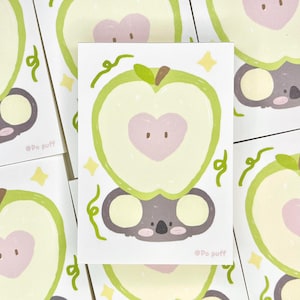 以下が含まれることがあります： 緑色のリンゴにピンク色のハートが描かれたものをかぶったコアラのイラストが描かれたカードが5枚セットになっています。カードは白地に薄い緑色のツルとキラキラ模様が描かれています。カードの右下には「@Po puff」の文字が書かれています。