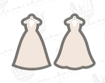 May include: Two cookie cutters shaped like wedding dresses with a hanger detail. The cutters are made of metal and have a light gray color.