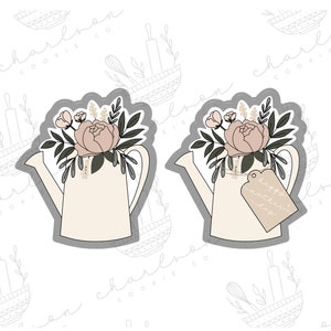 May include: Two white ceramic watering cans with a gray outline, each filled with a bouquet of pink and white flowers. One watering can has a tag that reads "Happy Mother's Day".