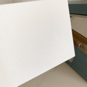 Puede incluir: Una superficie rectangular blanca texturizada. La superficie es lisa y tiene un brillo sutil.