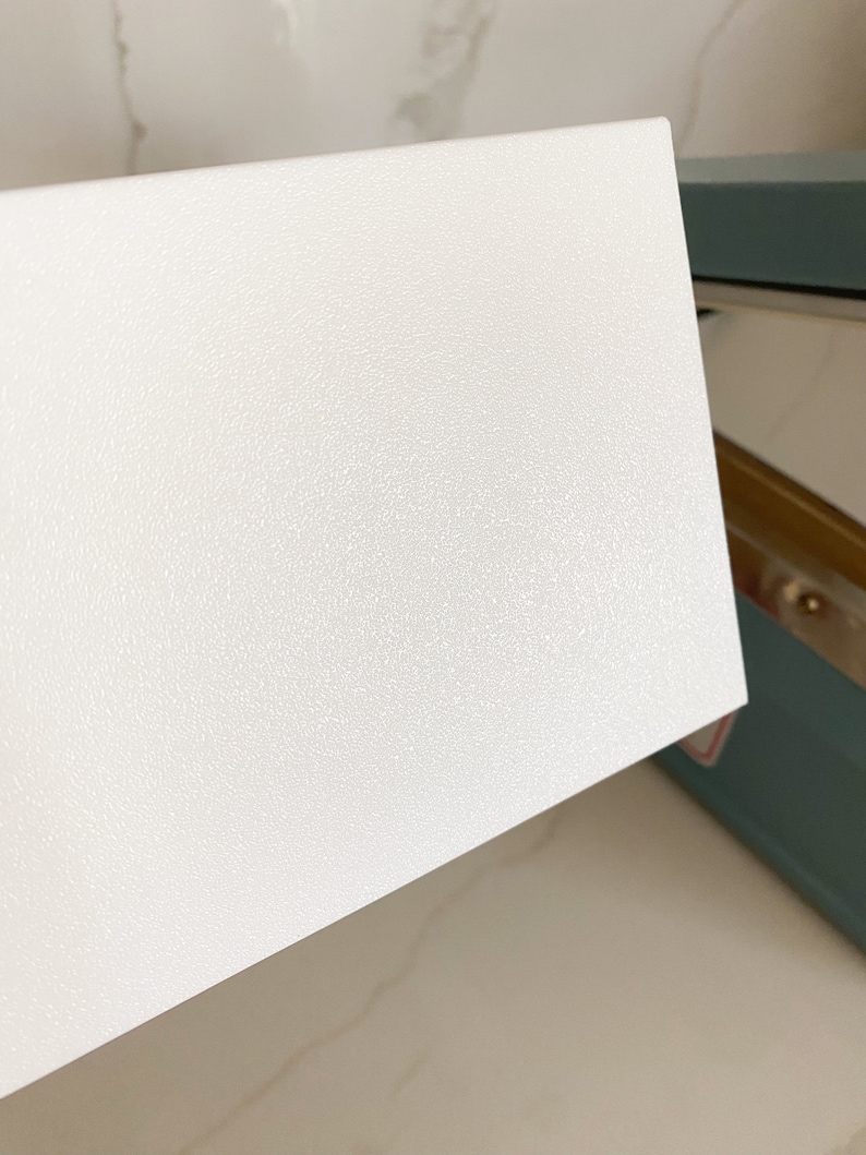 Puede incluir: Una superficie rectangular blanca texturizada. La superficie es lisa y tiene un brillo sutil.