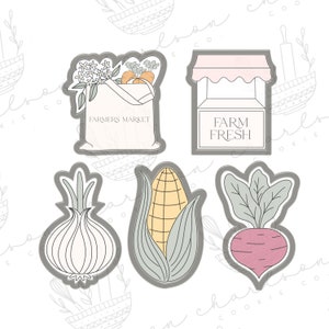 May include: Five cookie cutters in gray with white outlines. The cutters are shaped like a bag of groceries with the text "Farmers Market", a farm stand with the text "Farm Fresh", an onion, an ear of corn, and a beet.