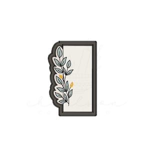 May include: A gray rectangular cookie cutter with a leafy design on the left side. The leaves are a light blue color with yellow flowers.