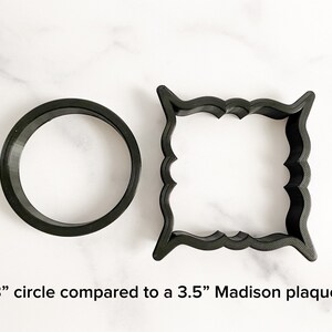 May include: A comparison of two cookie cutters: a 3-inch circle and a 3.5-inch Madison plaque. Both cutters are black and made of plastic.