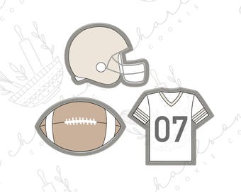 May include: A set of three cookie cutters in the shape of a football, a football helmet, and a football jersey with the number 07. The cookie cutters are gray and white.