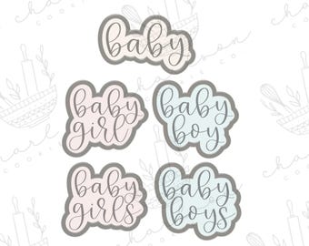 Puede incluir: Un conjunto de cinco cortadores de galletas con la forma de la palabra "baby" y sus variaciones. Los cortadores están en una fuente cursiva y están delineados en gris. También se incluyen las palabras "baby girl", "baby boy", "baby girls" y "baby boys".