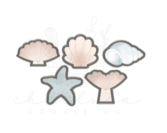 May include: Five cookie cutters in the shape of seashells, a starfish, and a mermaid tail. The cutters are outlined in gray and have a watercolor effect in shades of beige, blue, and white. The cookie cutters are arranged on a white background.