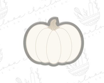 以下が含まれることがあります： グレーの輪郭のクッキーカッターの南瓜。南瓜は白く、茎があります。