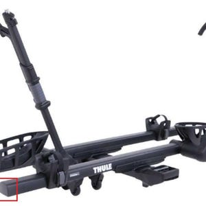 以下が含まれることがあります： 黒色のThule自転車ラック。2つの垂直アームと水平ベースを備えています。ラックは自転車の車輪を保持するためのバスケットのような構造をしています。「THULE」の文字がベースに印刷されています。