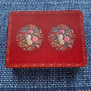 May include: A red rectangular tray with a gold border and floral designs. The tray has a distressed, crackled finish and features two bouquets of flowers in shades of pink, white, and green.