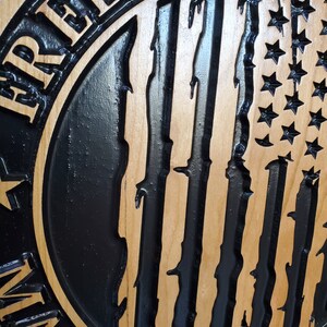 K&ouml;nnte beinhalten: Ein Holzschild mit einem schwarz-wei&szlig;en amerikanischen Flaggenmuster. Das Schild lautet "Freiheit ist nicht frei".