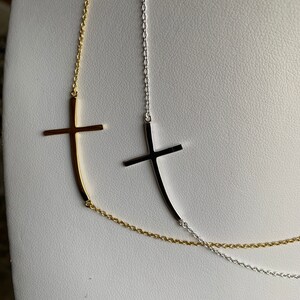May include: Two delicate necklaces with a simple cross pendant. One necklace is gold and the other is silver.