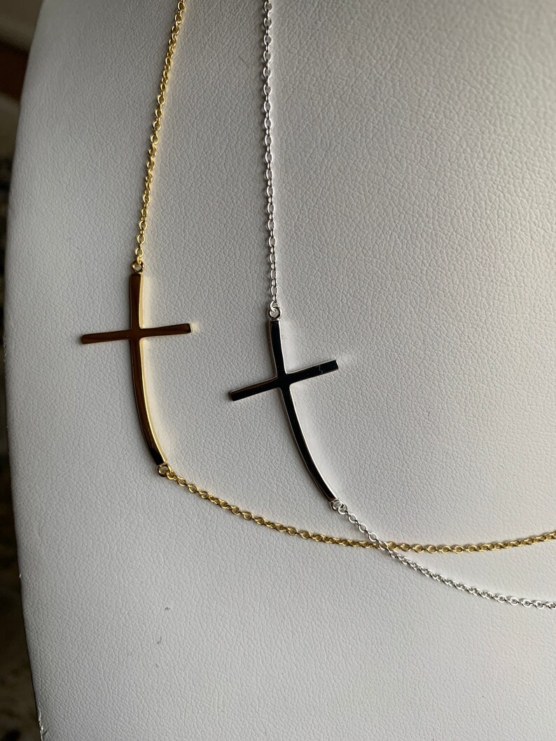 May include: Two delicate necklaces with a simple cross pendant. One necklace is gold and the other is silver.