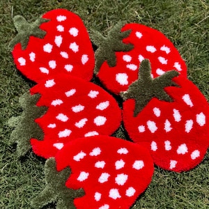 May include: Five red and white strawberry-shaped rugs with green leaves. The rugs are made of a soft, fuzzy material and are perfect for adding a touch of whimsy to any room.