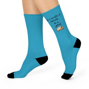May include: A pair of turquoise socks with black heels and toes. The socks feature the text "In a world of cannots, be a cannoli" with a graphic of cannoli pastries.