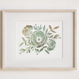 May include: A framed floral print featuring a bouquet of stylized flowers and leaves in shades of green, gold, and brown. The artwork is set against a white background and framed in a light wood frame, creating a natural and elegant aesthetic.