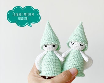 May include: Two crocheted green and white gnomes with smiling faces. The gnomes are holding hands and have pointy hats.