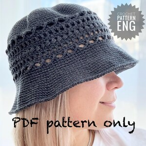 Pode incluir: Um chapéu de balde de crochê cinza escuro com uma aba larga e detalhes vazados. O chapéu é usado por uma pessoa. A imagem inclui o texto "CROCHET PATTERN ENG" e "PDF pattern only".
