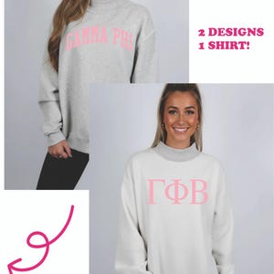 May include: Reversible sweatshirt in light gray and white with pink Greek letters. One side reads "GAMMA PHI" and the other side reads "ΓΦB". The text "2 DESIGNS 1 SHIRT!" and "IT'S REVERSIBLE" are also visible.
