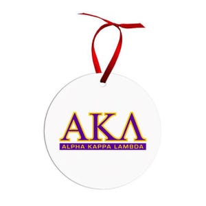 May include: White round ornament with the letters AKA in purple and gold, with the words ALPHA KAPPA LAMBDA below. A red ribbon is attached at the top for hanging.