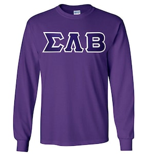 May include: A long-sleeved purple t-shirt with the Greek letters ΣΛB in white with a dark purple outline. The shirt is made of a soft material and has a crew neck. The sleeves are long and end in a ribbed cuff.
