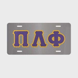 May include: A rectangular gray license plate featuring the Greek letters Pi, Lambda, and Phi in purple with a gold outline. The plate has four mounting holes, one in each corner, and a smooth, metallic finish across the entire surface area.