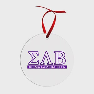 May include: A circular white ornament featuring the purple Greek letters Sigma Lambda Beta and the text Sigma Lambda Beta in a purple rectangle. The ornament is suspended by a thin red ribbon tied in a bow at the top for hanging purposes.
