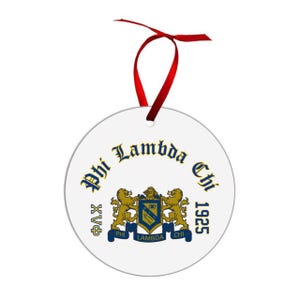 May include: A white, round ornament with a red ribbon for hanging. The ornament features the text "Phi Lambda Chi 1925" in blue and gold, along with a crest with two gold lions.
