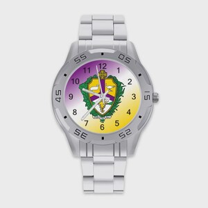 May include: A silver-toned analog wristwatch with a metal link band. The watch face features a gradient background transitioning from purple to yellow, displaying a central crest with a shield, a cross, a lamp, and a sunburst design.