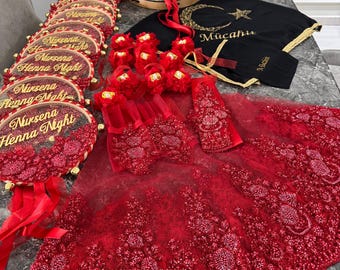 Puede incluir: Decoraciones de noche de henna rojas y doradas, que incluyen un velo rojo con bordados dorados, un pandero con el texto "Nursena's Henna Night" y una tela negra con un diseño de media luna y estrella y el texto "Mucahidde".