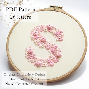 Puede incluir: Un bastidor de bordado de madera que contiene tela de color blanco roto con una letra S bordada en varios tonos de patrones florales rosas. El texto en la imagen dice: PDF Pattern 26 letters, Original Embroidery Design, Handmade by Artist, No AI Generated Content.